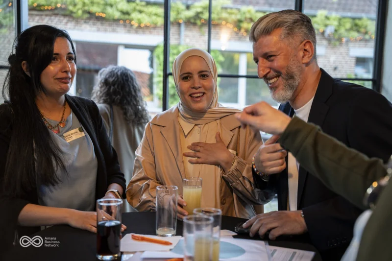 Drie gasten in gesprek aan een tafel bij het raam